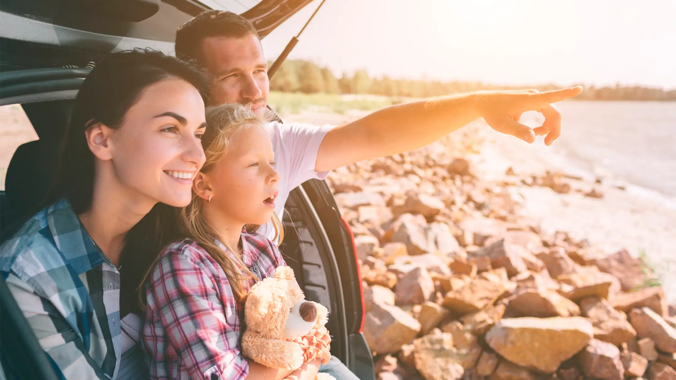 Familia sentada en la parte trasera de una vehiculo estacionado sobre la bahia